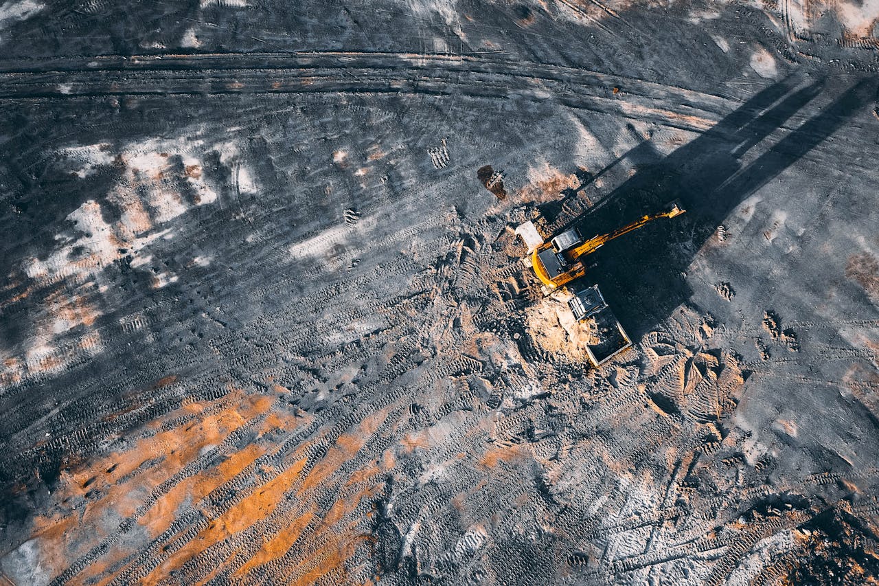 Aerial view of excavator working on big coal field of powerplant located in countryside